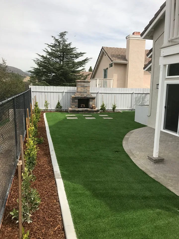 Custom outdoor stone fireplace with synthetic turf and continuous curbing in El Cajon CA